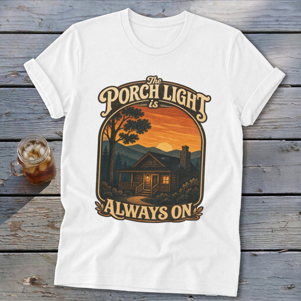 White t-shirt with "The Porch Light is Always On" graphic featuring a cabin at sunset.