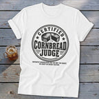 A white t-shirt featuring a circular graphic with text reading Certified Cornbread Judge.