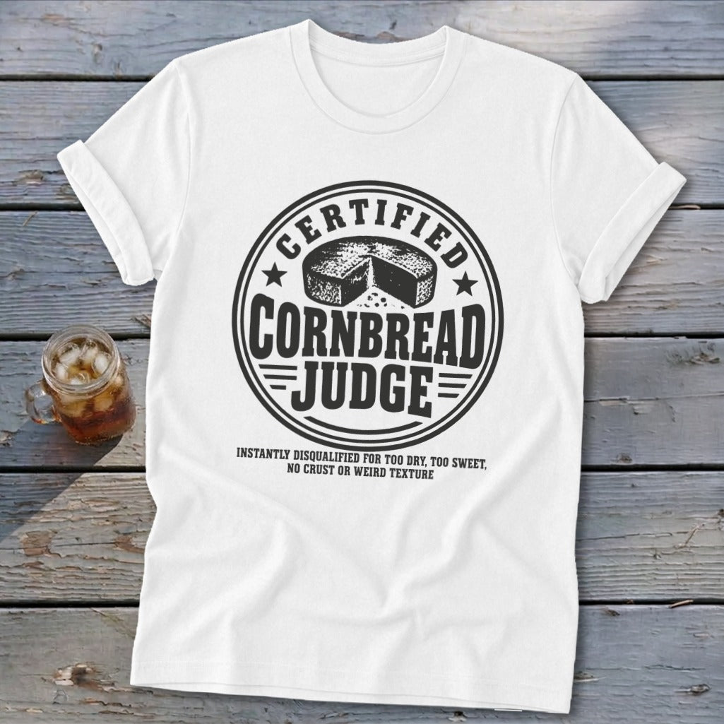 A white t-shirt featuring a circular graphic with text reading Certified Cornbread Judge.