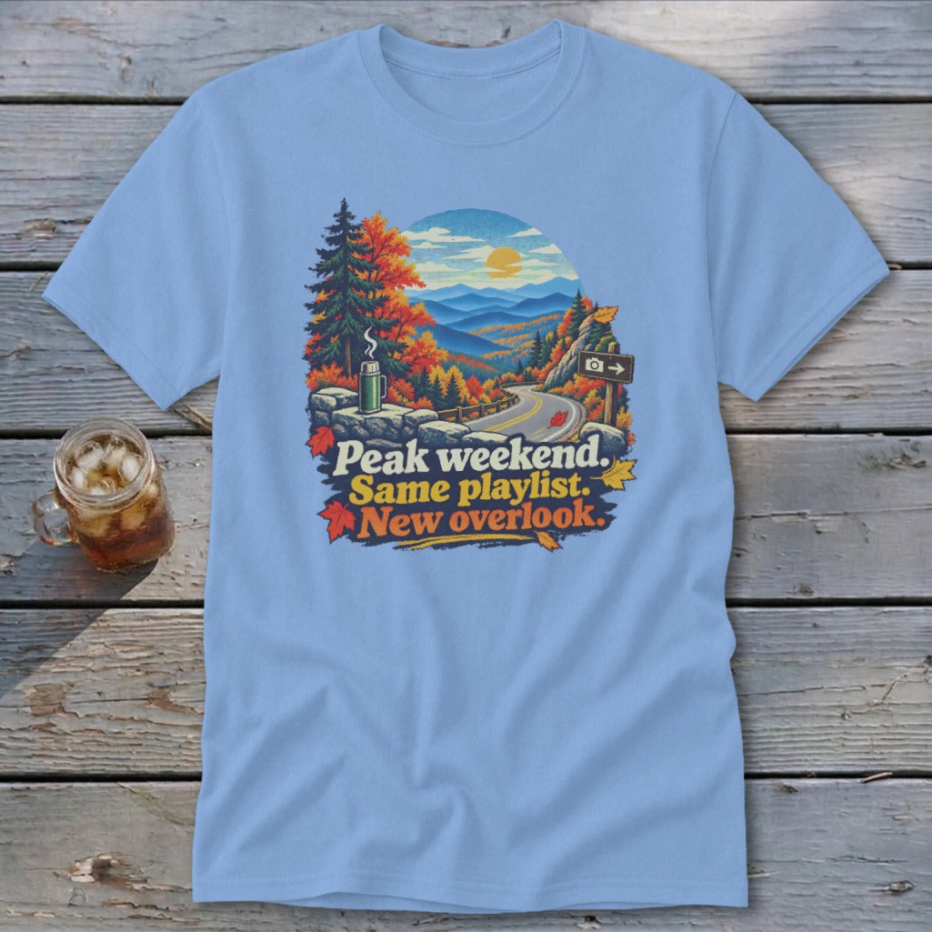 T-shirt with mountain landscape, autumn leaves, and text "Peak weekend. Same playlist. New overlook."