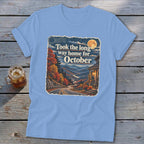 Blue t-shirt with autumn landscape graphic and text "Took the long way home for October".
