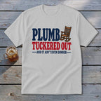 White t-shirt with "PLUMBER TUCKERED OUT" and rocking chair graphic.