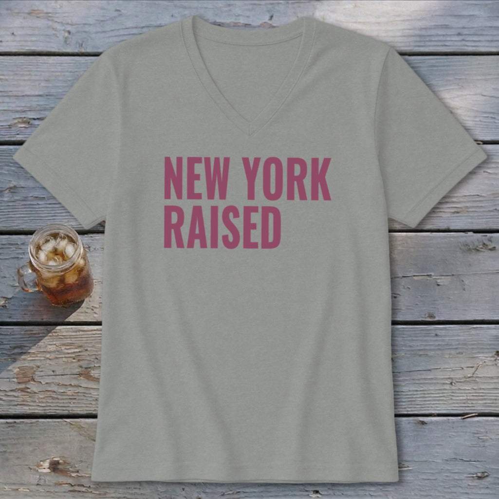 Grey v-neck t-shirt with pink "NEW YORK RAISED" text and a glass of iced tea.