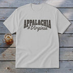 White t-shirt with "APPALACHIA #Virginia" text in dark gray on a wooden surface.