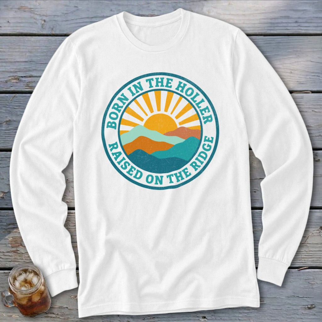 White long-sleeve t-shirt with a round retro mountain and sun graphic featuring the text Born in the Holler Raised on the Ridge.