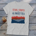 Light gray t-shirt with rolled sleeves featuring red, white, and blue patriotic graphic text and fireworks.