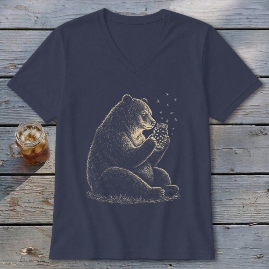 Bear holding a jar of fireflies with stars around it on a navy shirt.