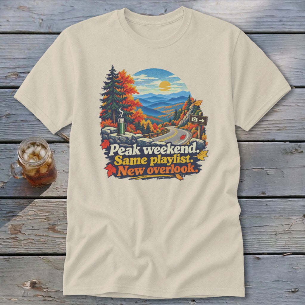 T-shirt graphic: Autumn mountain road with text "Peak weekend. Same playlist. New overlook."