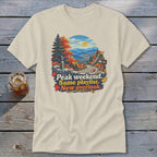 T-shirt graphic: Autumn mountain road with text "Peak weekend. Same playlist. New overlook."