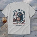 White t-shirt graphic of a bear stirring a pot of apple butter with "Hollerbear Apple Butter Season" text.