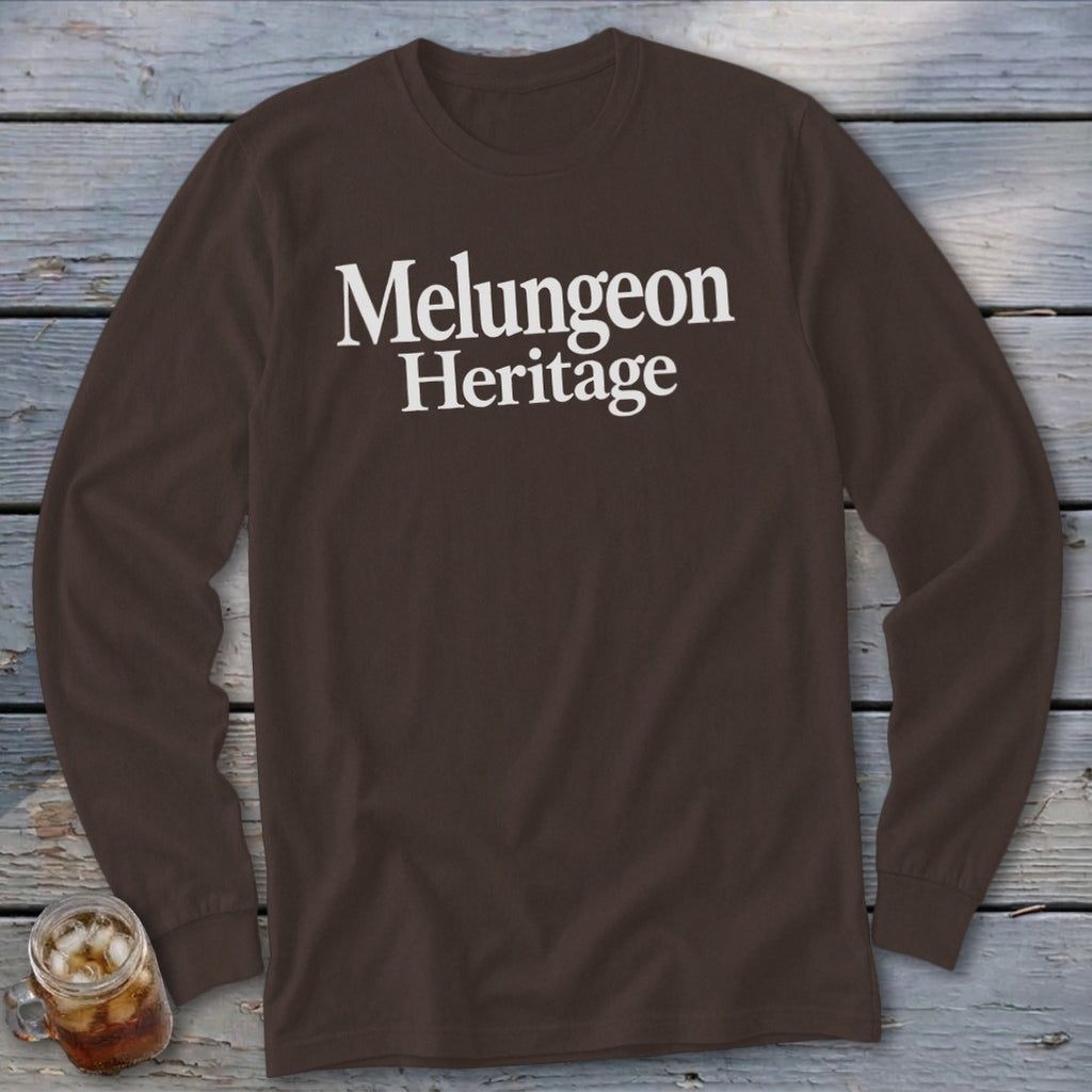 Dark brown long-sleeve t-shirt with white text reading Melungeon Heritage on a rustic wooden background.