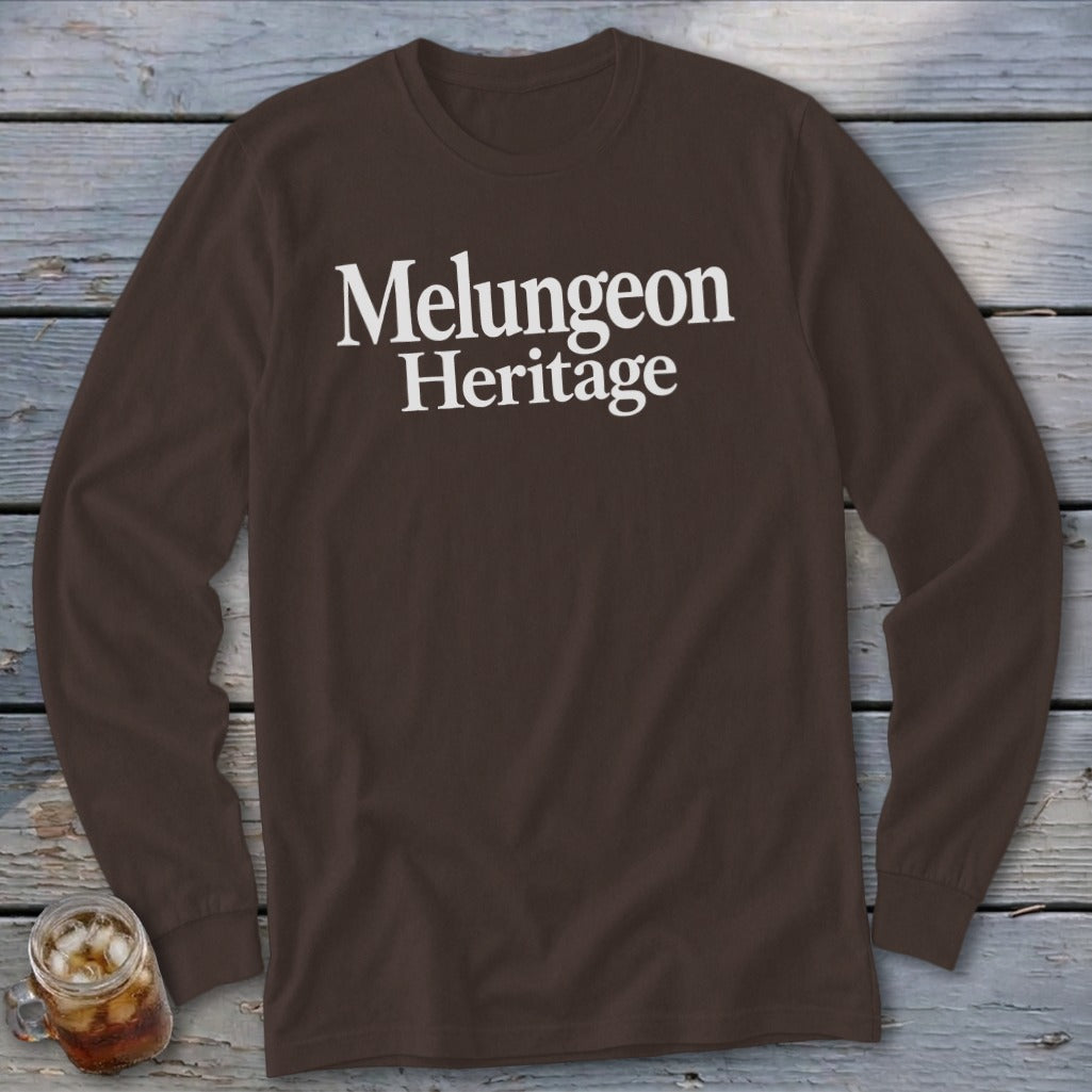 Dark brown long-sleeve t-shirt with white text reading Melungeon Heritage on a rustic wooden background.