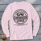 Light pink long-sleeved t-shirt with a round emblem reading Certified Cornbread Judge and humorous disqualification criteria.