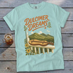 Light blue t-shirt with "Dulcimer Dreams" text and a dulcimer on a porch railing.