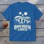 Blue short-sleeve t-shirt with a white graphic of three figures, mountains, and glowing lights.