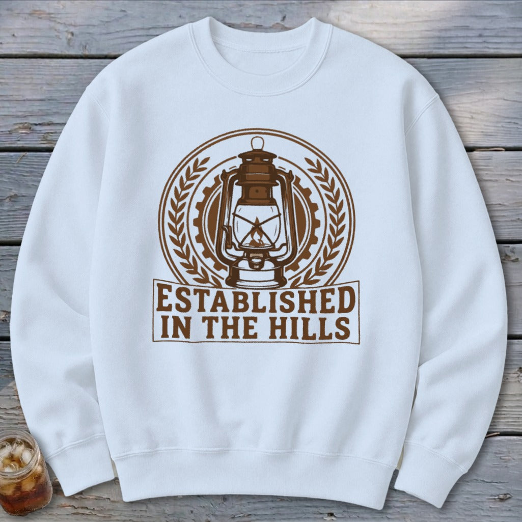White sweatshirt with brown vintage lantern emblem and "ESTABLISHED IN THE HILLS" text.