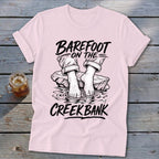 Pink t-shirt with graphic of bare feet on rocks in water, "Barefoot on the Creek Bank" text.