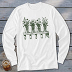 A white long-sleeved t-shirt featuring a green graphic of four mason jars filled with wildflowers on a wooden shelf.