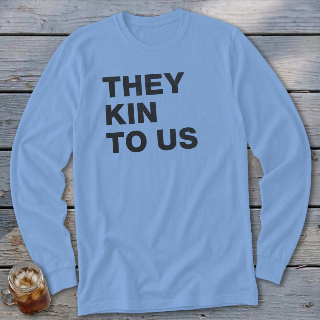 Light blue long sleeve shirt with black text "THEY KIN TO US".