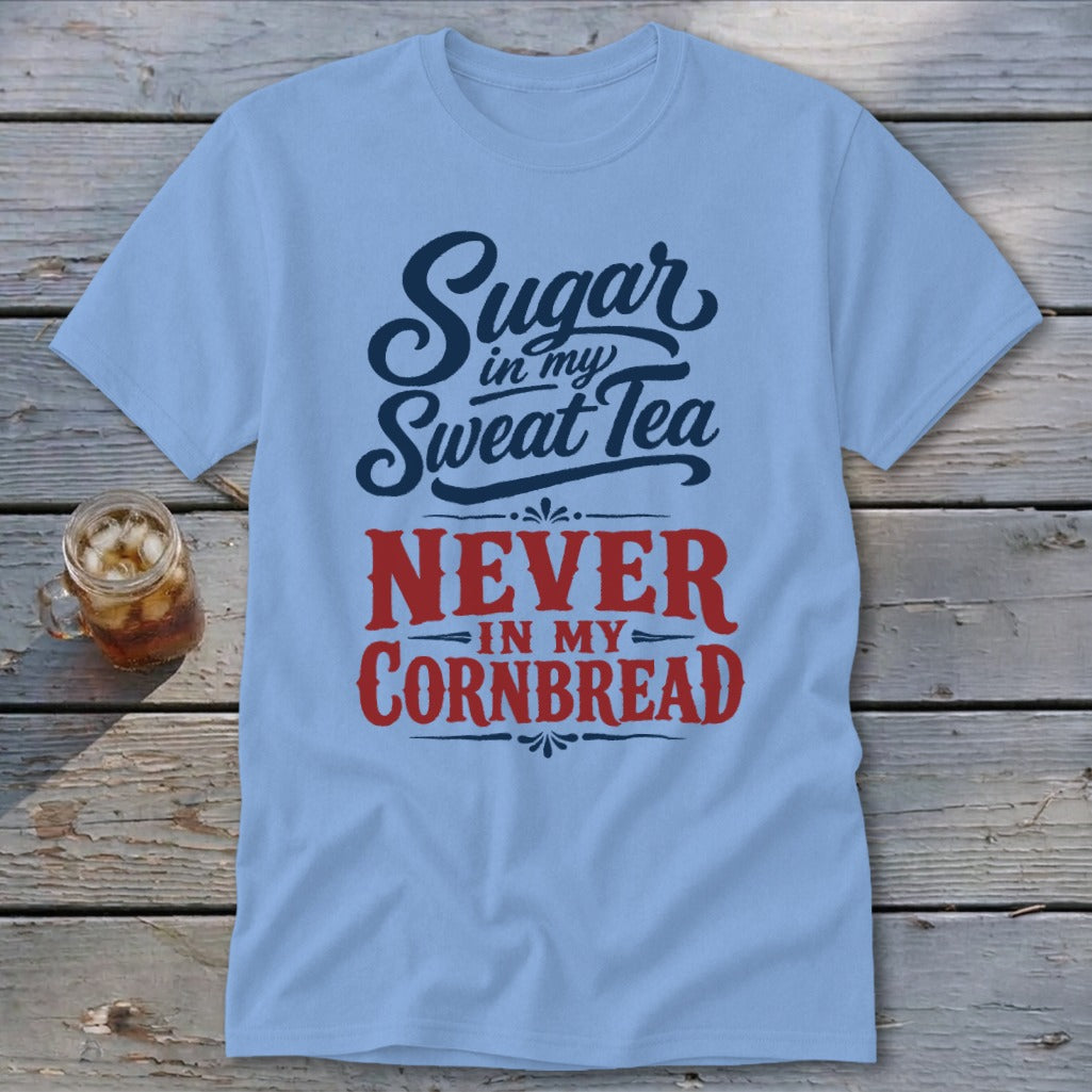 Light blue t-shirt featuring the text Sugar in my Sweat Tea NEVER IN MY CORNBREAD on a wooden surface.