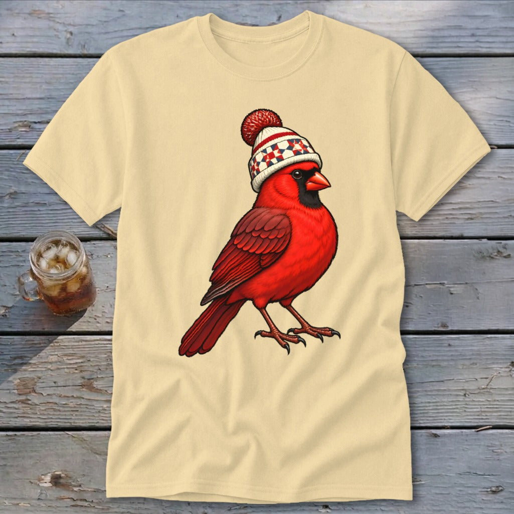 Beige short-sleeve t-shirt featuring a graphic of a red cardinal wearing a winter hat with a pom-pom.