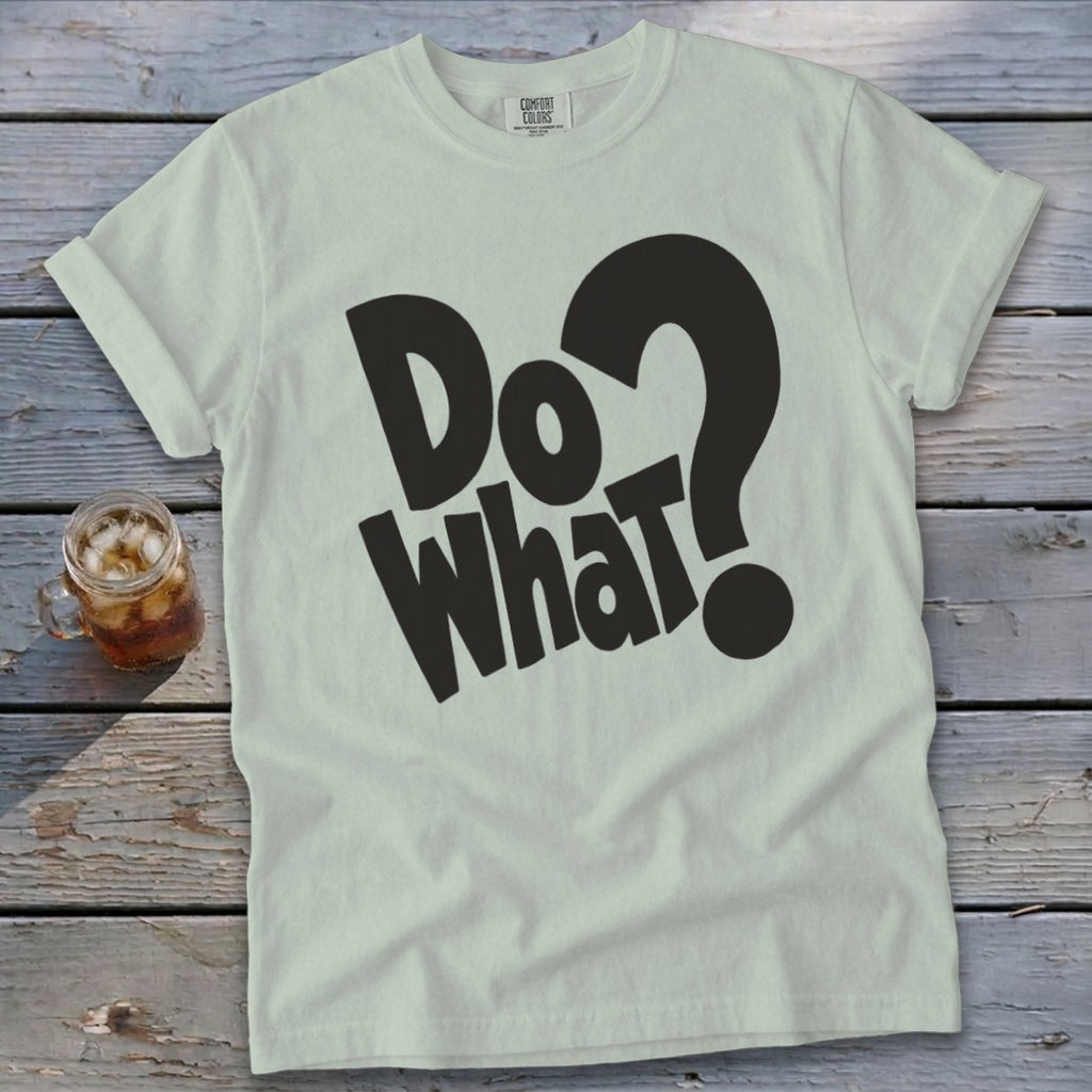 Light sage green t-shirt with rolled sleeves featuring bold black text reading Do What? on wooden surface.