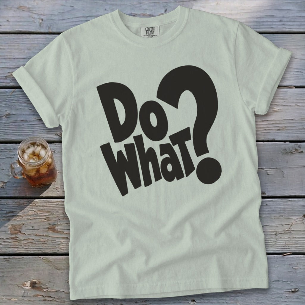 Light sage green t-shirt with rolled sleeves featuring bold black text reading Do What? on wooden surface.