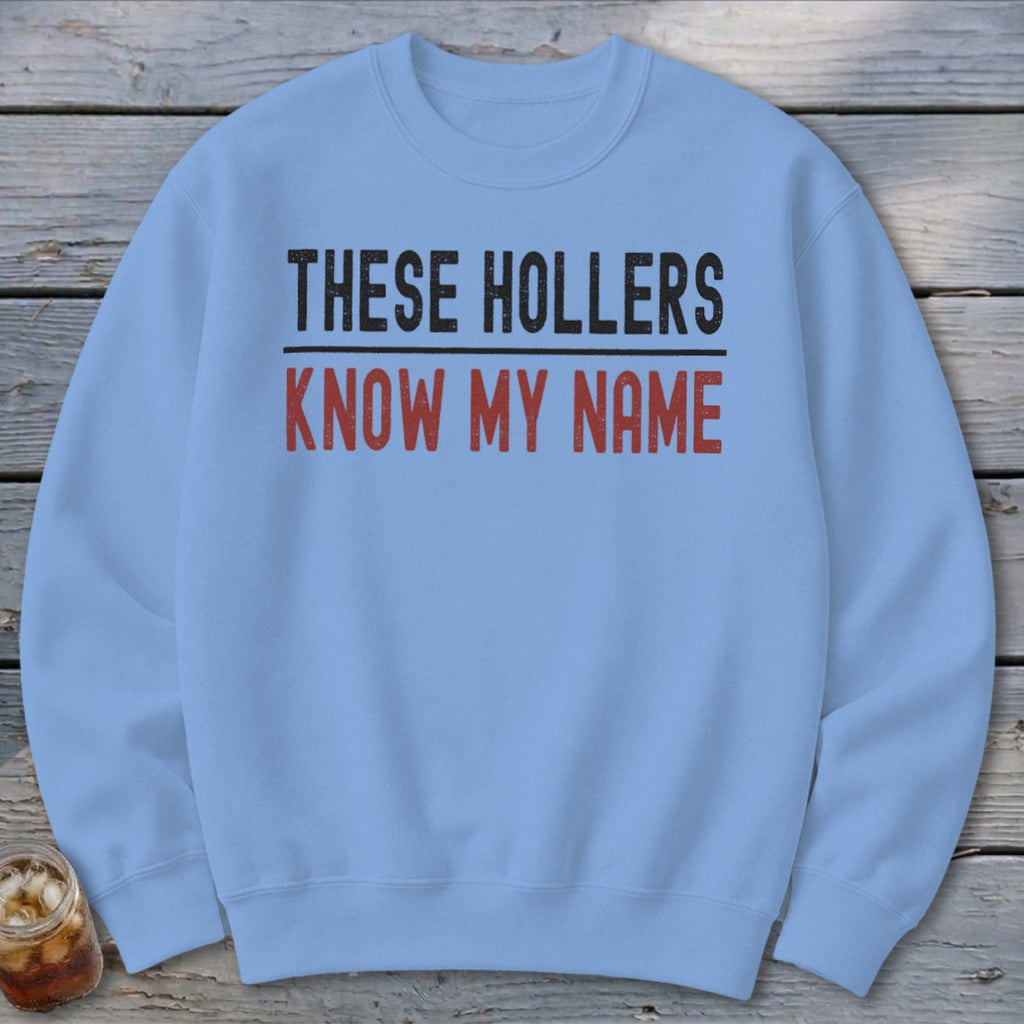 Light blue sweatshirt with "THESE HOLLERS KNOW MY NAME" text.