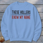 Light blue sweatshirt with "THESE HOLLERS KNOW MY NAME" text.