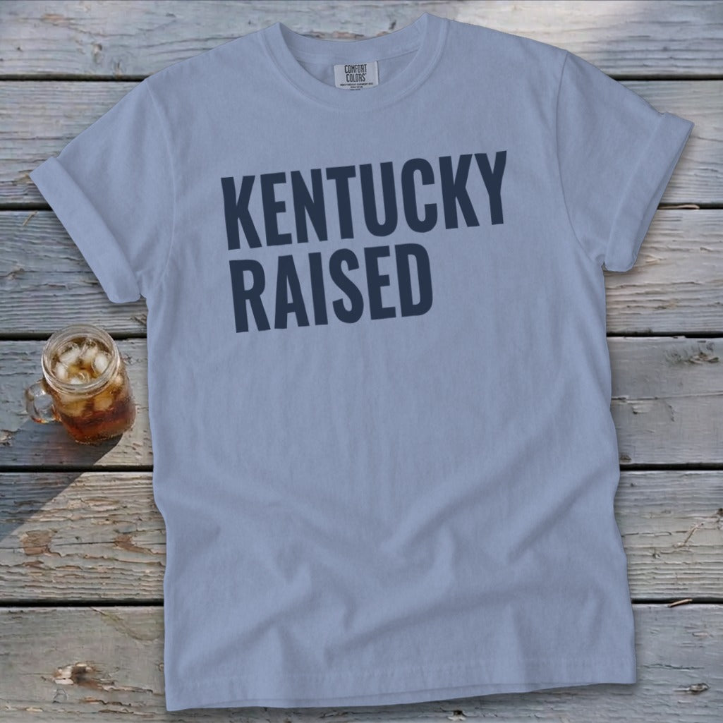 Light blue t-shirt with dark blue text "Kentucky Raised" and a glass of iced tea.