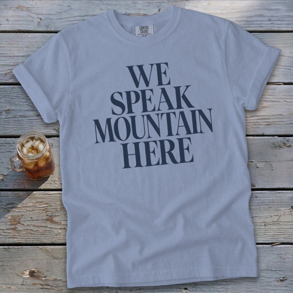 Light blue t-shirt with "WE SPEAK MOUNTAIN HERE" graphic and a drink.