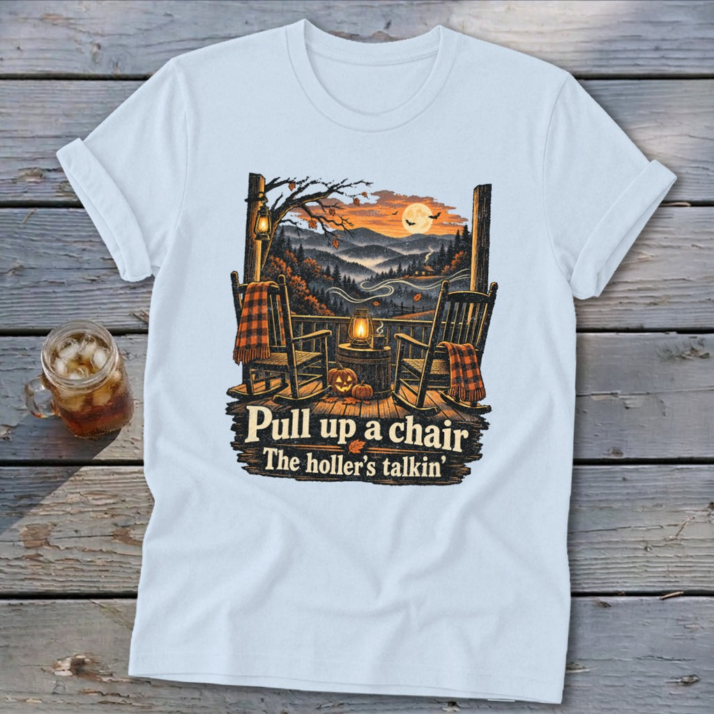 Light blue t-shirt with rocking chairs, pumpkins, and autumn mountains. Text: "Pull up a chair The holler's talkin'".