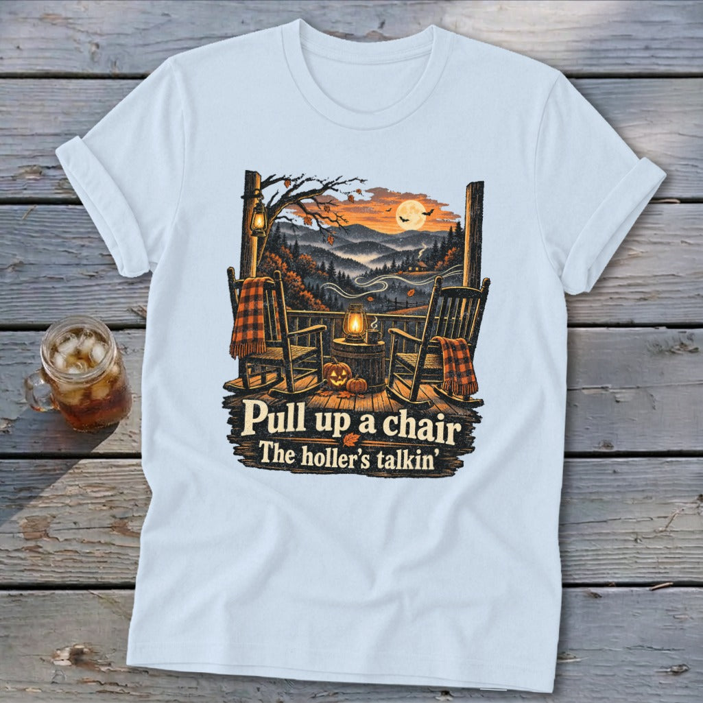 Light blue t-shirt with rocking chairs, pumpkins, and autumn mountains. Text: "Pull up a chair The holler's talkin'".