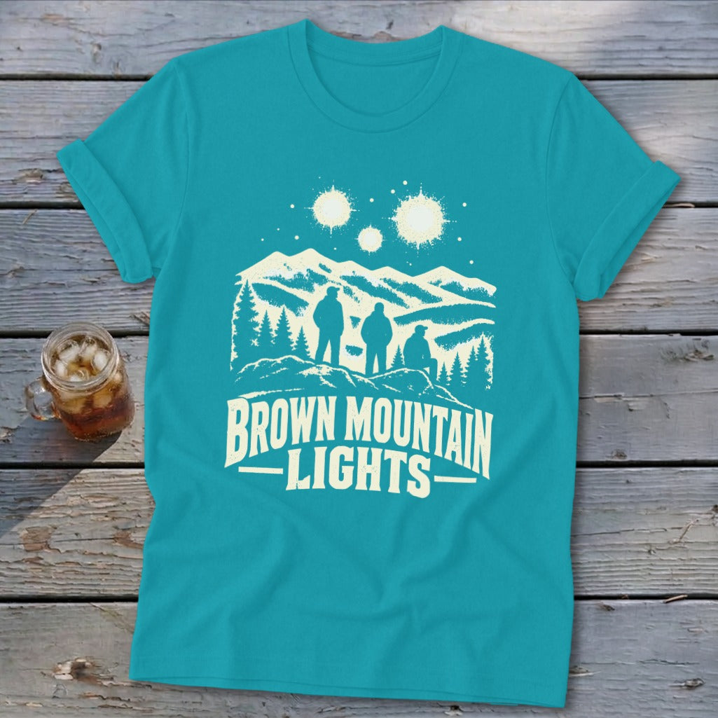 Teal crewneck t-shirt featuring a graphic of three figures looking at glowing lights above mountains.