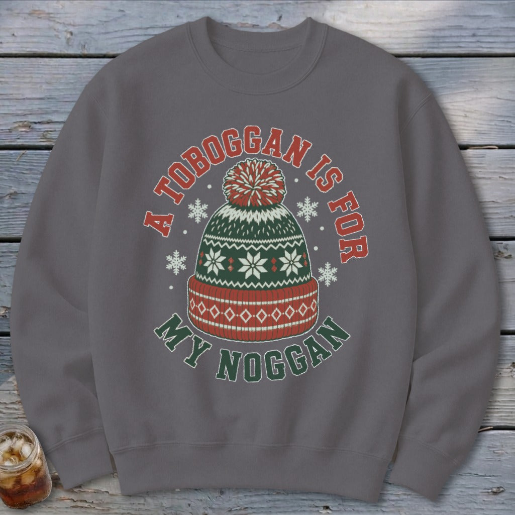 A dark gray crewneck sweatshirt featuring a winter hat graphic with the text A TOBOGGAN IS FOR MY NOGGAN.