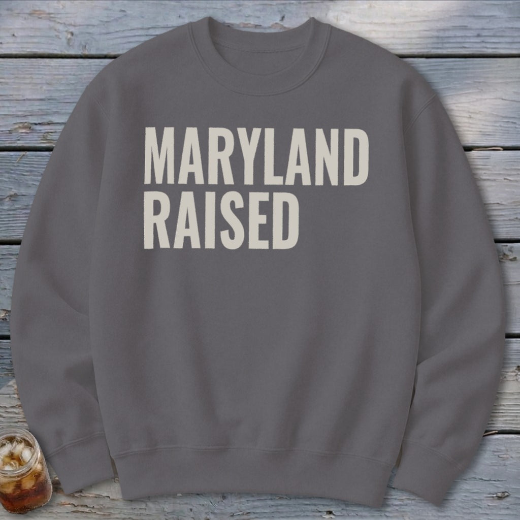 Gray sweatshirt with cream text reading "MARYLAND RAISED".