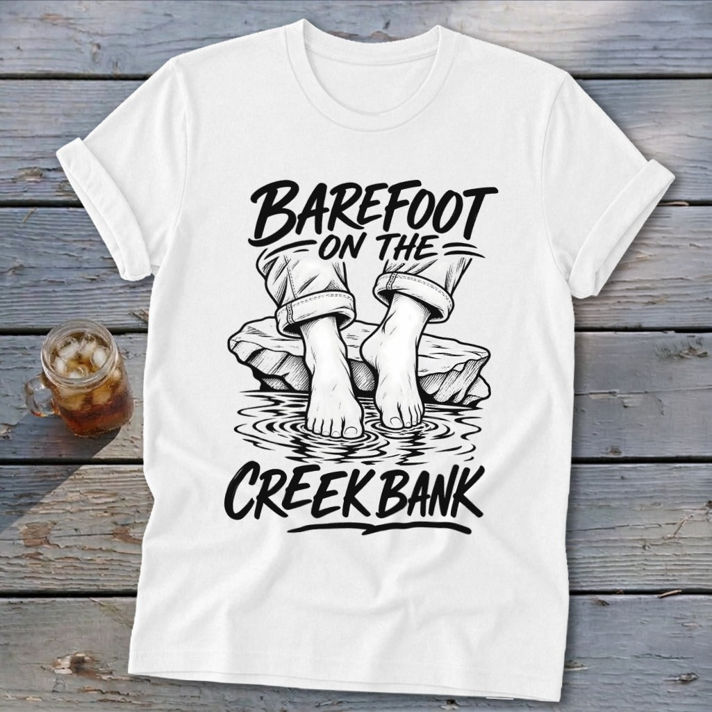 White t-shirt graphic with "Barefoot On The Creek Bank" text and bare feet in water.