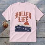 Light pink short-sleeved t-shirt with orange text reading HOLLER LIFE above a stylized mountain sunset graphic.