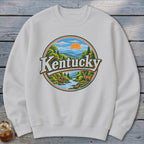 White sweatshirt with a circular graphic of Kentucky landscape with a deer and river.
