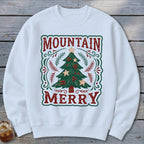 White crewneck sweatshirt featuring a graphic of a Christmas tree with the text Mountain Merry.