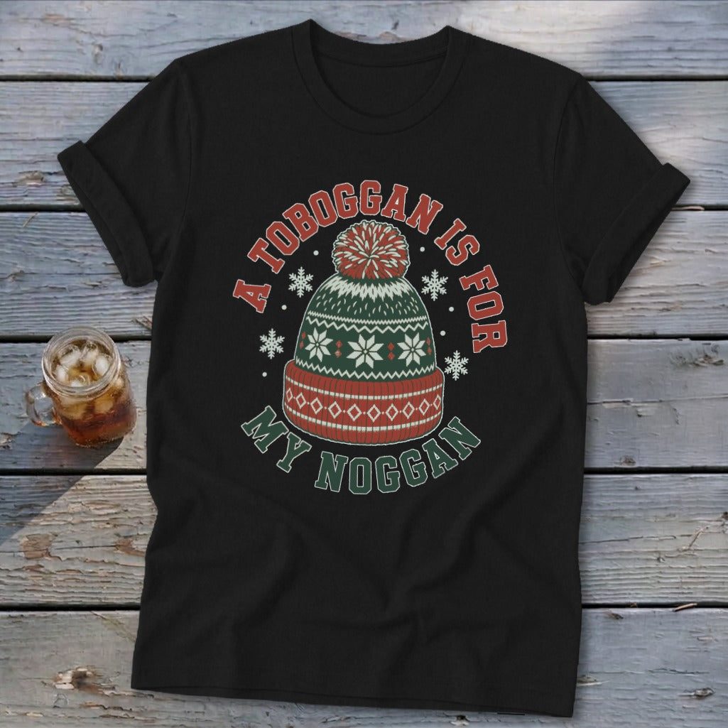 A black t-shirt with a graphic of a winter hat and the text A TOBOGGAN IS FOR MY NOGGAN.