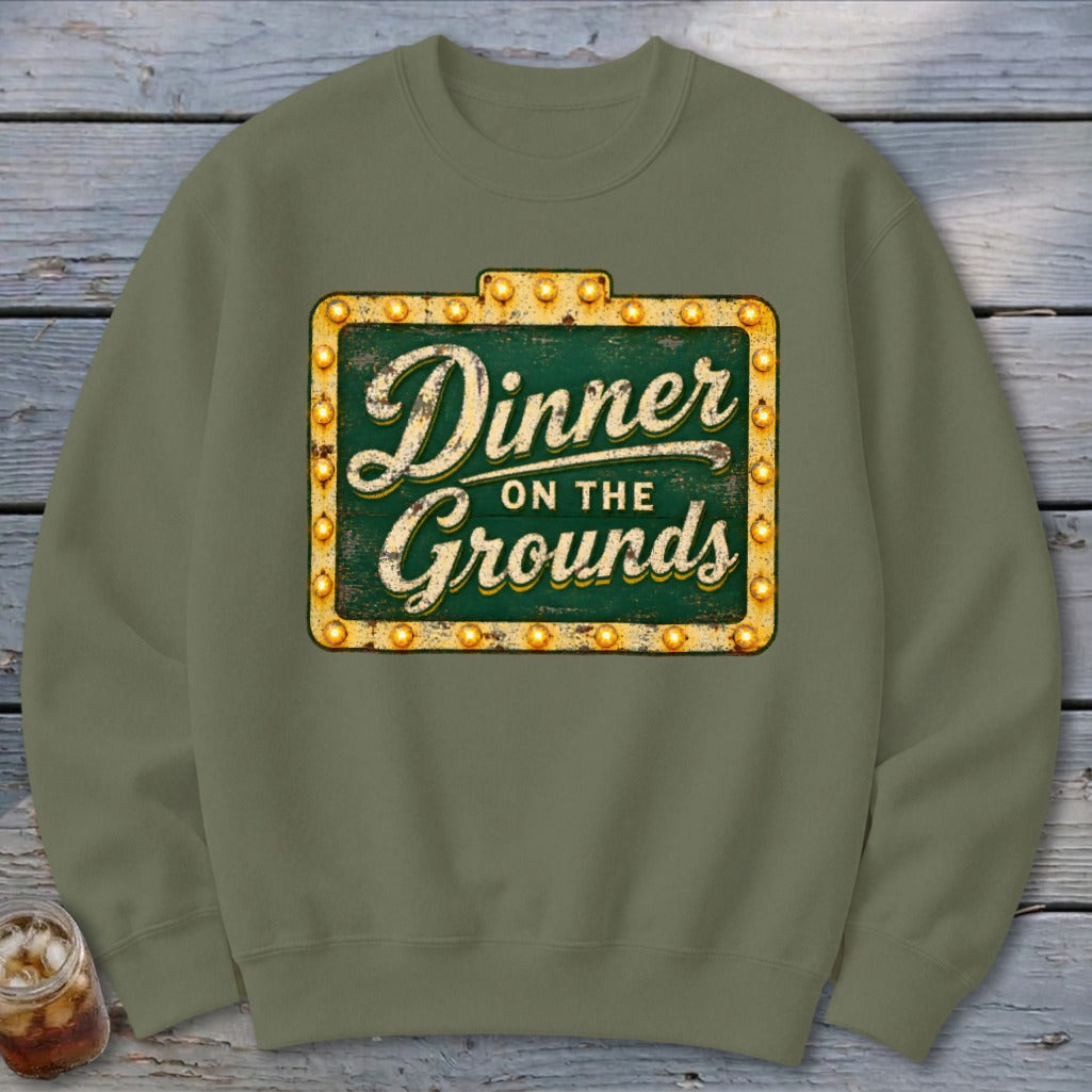 Olive green crewneck sweatshirt featuring a distressed marquee sign graphic that reads Dinner on the Grounds.