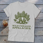 White t-shirt with green illustration of morel mushrooms and text "WILD FORAGED APPALACHIA".