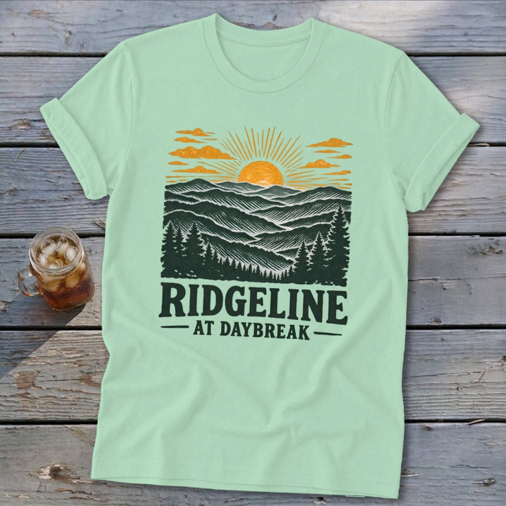 Mint t-shirt with a graphic of a sunrise over mountains and the text "RIDGELINE AT DAYBREAK".