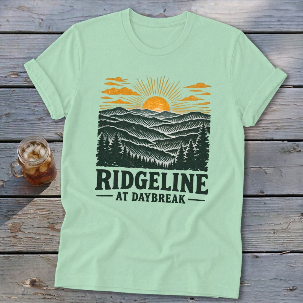 Mint t-shirt with a graphic of a sunrise over mountains and the text "RIDGELINE AT DAYBREAK".