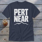 A dark blue crewneck t-shirt featuring the white text PERT NEAR above a mountain range graphic.