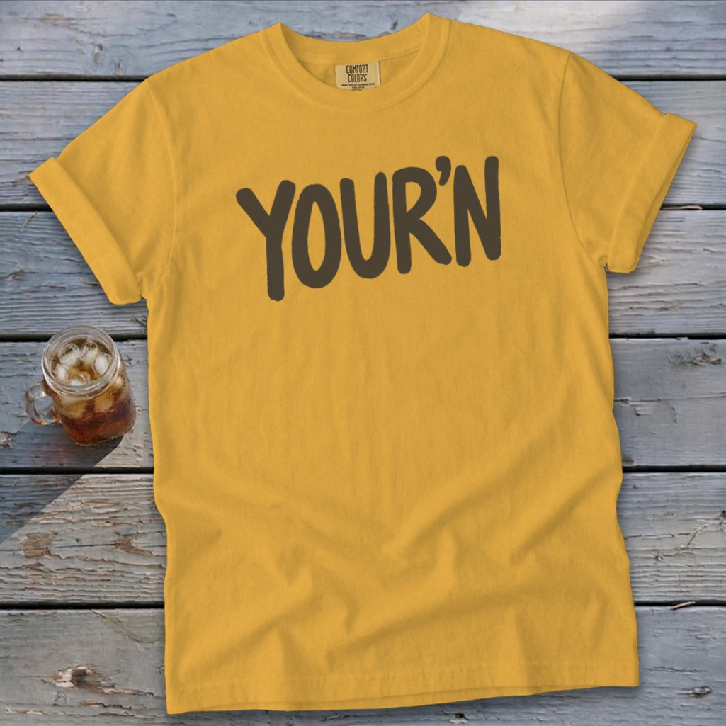Yellow t-shirt with brown text reading "YOUR'N" and a glass of iced beverage.