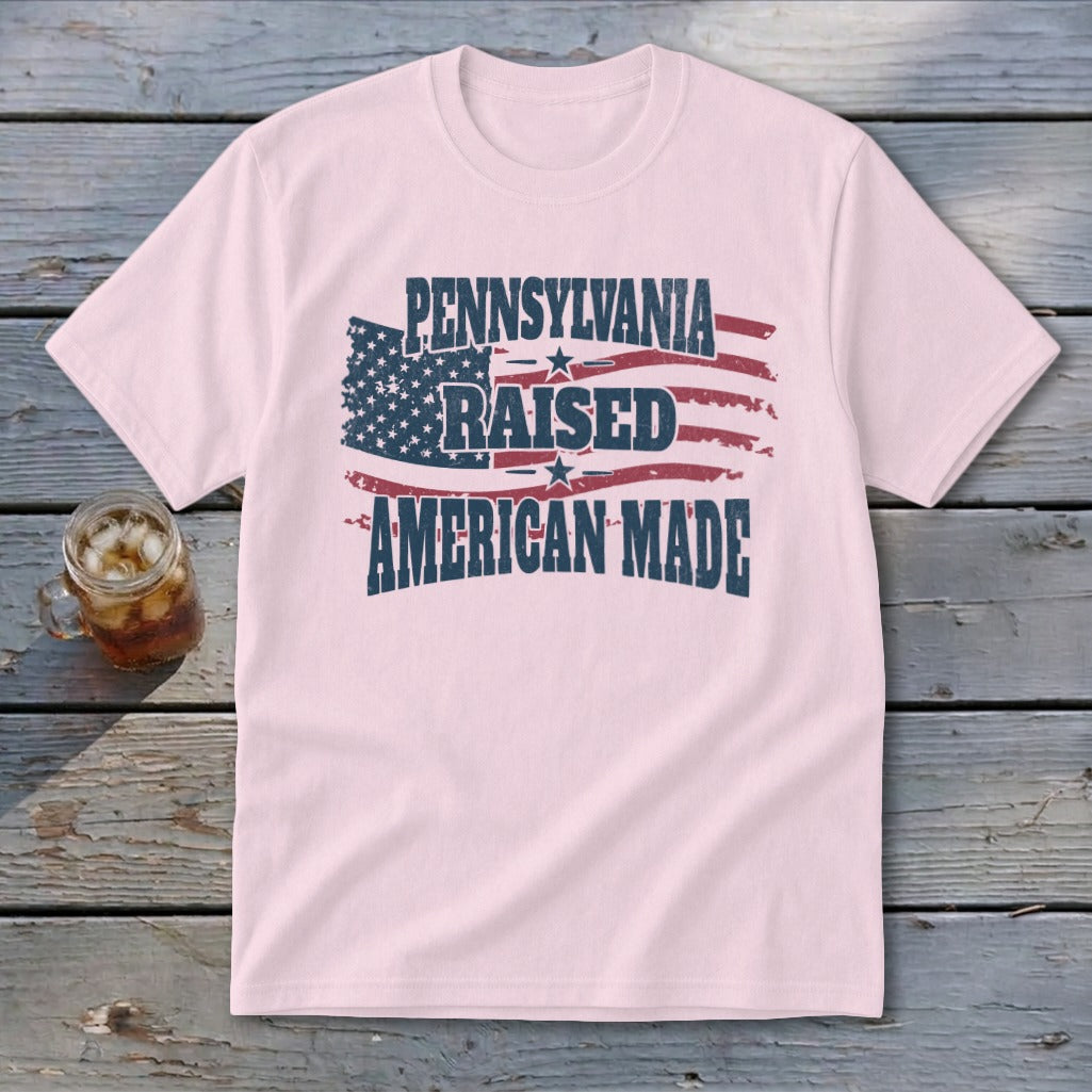 A light pink t-shirt featuring the text Pennsylvania Raised American Made over a distressed American flag design.