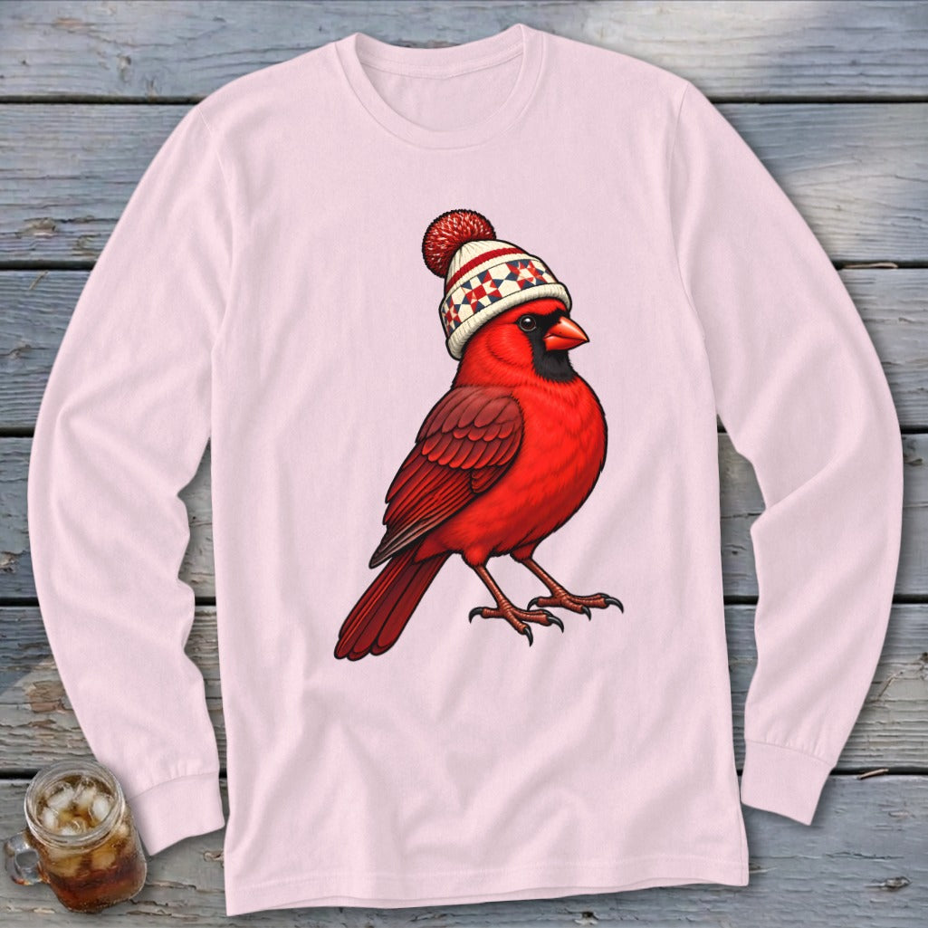 Light pink long-sleeve t-shirt featuring an illustration of a red cardinal wearing a winter hat.