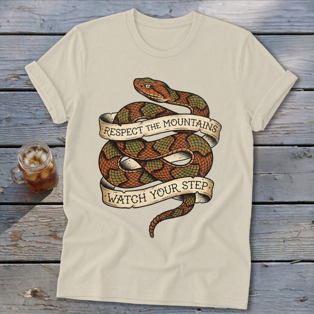 Cream t-shirt with coiled snake and banners reading "Respect the Mountains" and "Watch Your Step".